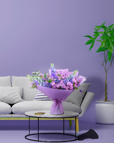 Bouquet of flowers on a coffee table with a gray sofa and green plant in the background.